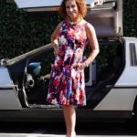 Claudia Wells in a Floral Dress Poses by a DeLorean Outside of Her Shop Armani Wells Men’s Clothing Store in Studio City